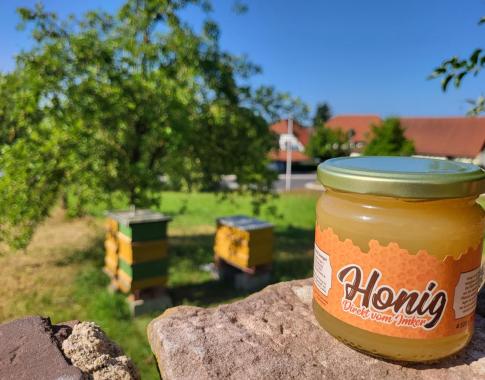 Im Hintergrund zu sehen: der Standort der Bienen. Durch die natürliche Kristallisation des Honigs kann sich die Konsistenz und Farbe noch ändern.