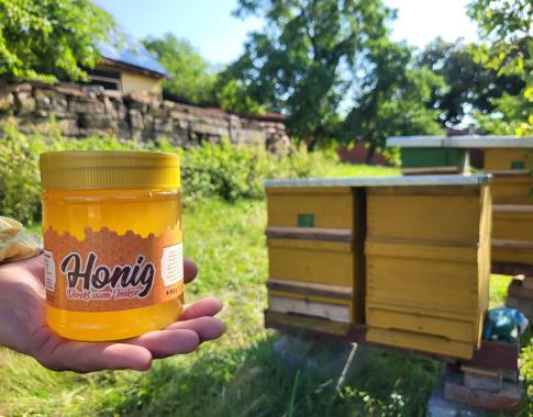 Im Hintergrund zu sehen: der Standort der Bienen. Durch die natürliche Kristallisation des Honigs kann sich die Konsistenz und Farbe noch ändern.
