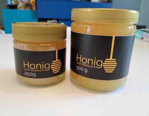 Ein großes und ein kleines Honigglas, Schwarzes Etikett, goldene Schrift und Honignehmer als Aufdruck