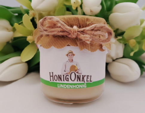 Lindenhonig auf Tisch mit Tulpen und Lindenblüten im Hintergrund