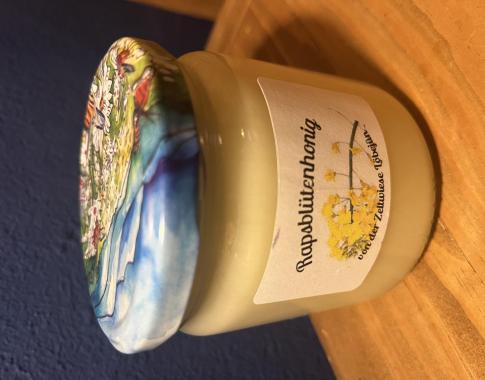 Ein Honigglas mit 500g Rapshonig mit Edikett und buntem Deckel